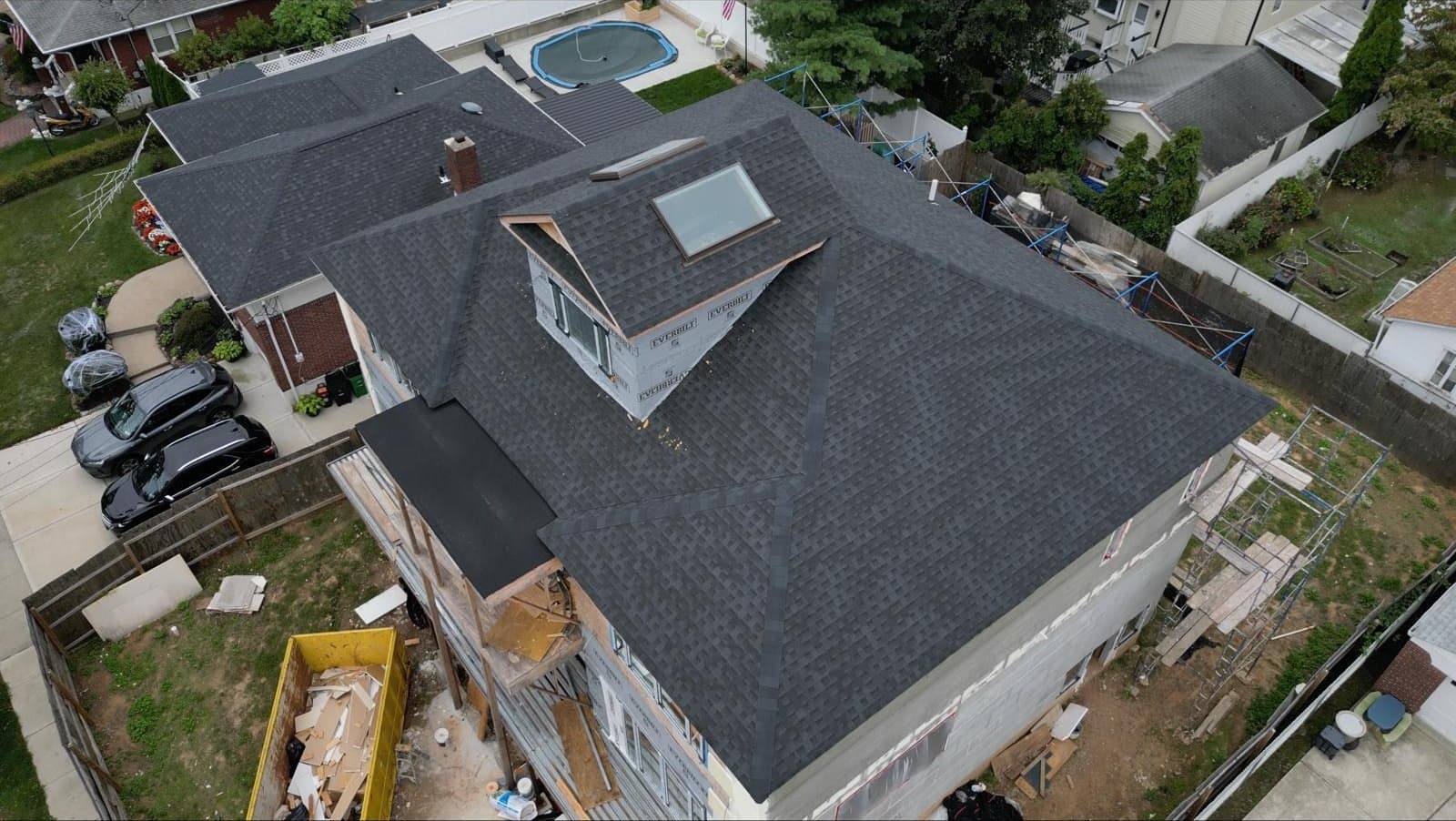 Mid-construction roof on Staten Island duplex with skylight and center dormer during shingle install