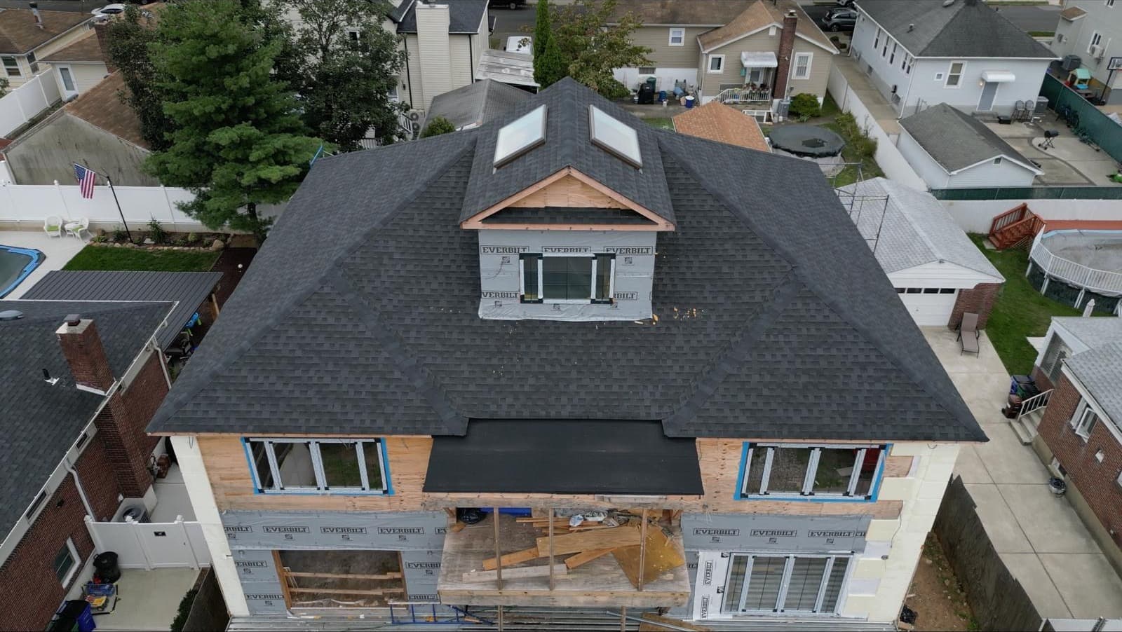 Staten Island duplex wrapped in building wrap with gabled center dormer and fresh shingle roof