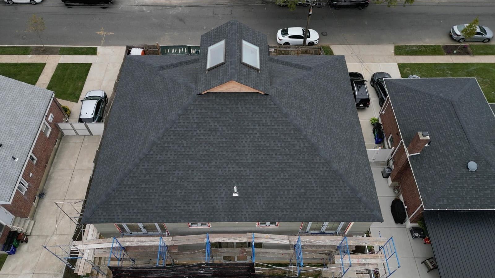Staten Island duplex with prominent front bay dormer and scaffolding across front elevation