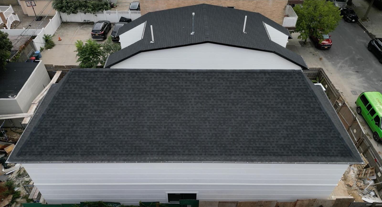 Brooklyn duplex showing pitched shingle main roof meeting flat rear extension