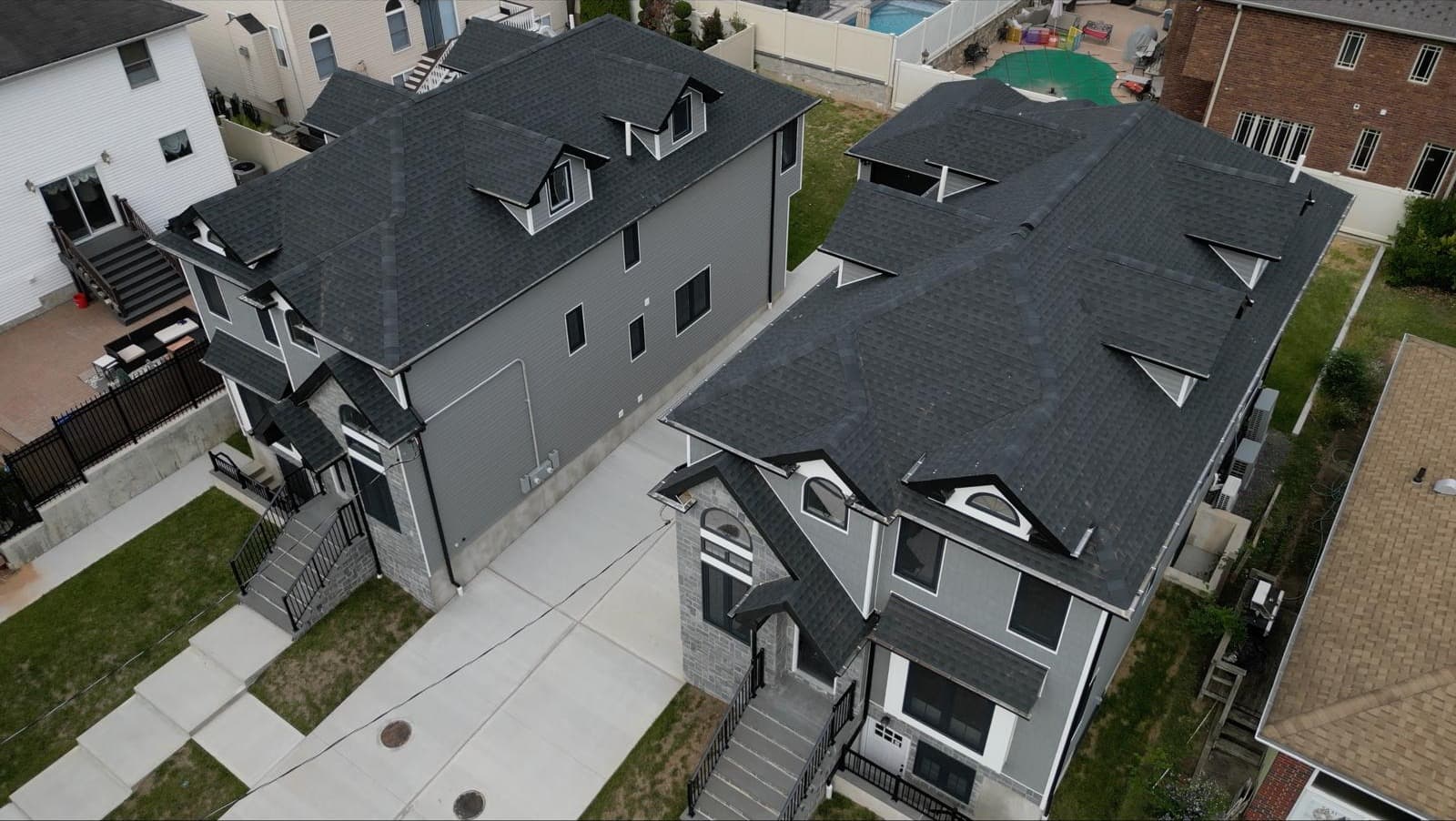 Rear angle of gray three-story duplex with multi-dormer roof